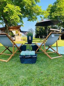 - deux chaises et un parasol sur l'herbe dans l'établissement Rooms & Apartment ZALA Airport shuttle option, à Cerklje na Gorenjskem