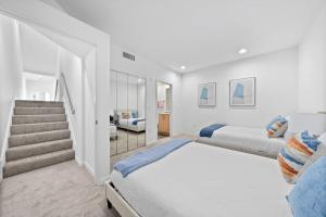 a white bedroom with two beds and a staircase at Penthouse Waterfront In the Heart of MDR/Venice/SM in Los Angeles