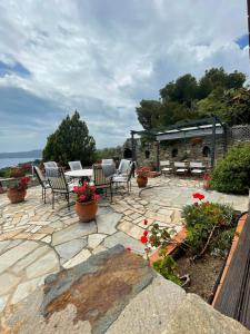 a patio with chairs and a table and a stone fireplace at villa athos in Sarti
