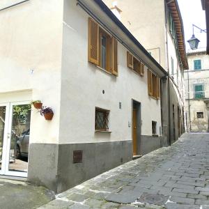 a white building with brown shutters on a street at Casa Girolamo in Acquapendente