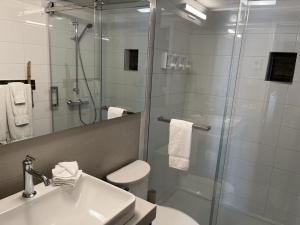 a bathroom with a shower and a sink and a toilet at Manoir Belle Plage in Carleton-sur-Mer