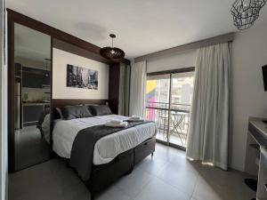 a bedroom with a large bed and a large window at Almada Studios 9 - República in São Paulo