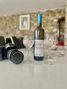 eine Flasche Wein und zwei Gläser auf dem Tisch mit Kamera in der Unterkunft Holiday house ISIDORA in Danilovgrad