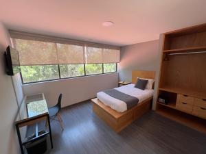 um quarto com uma cama e uma grande janela em Bonsai Las Aguilas em Cidade do México