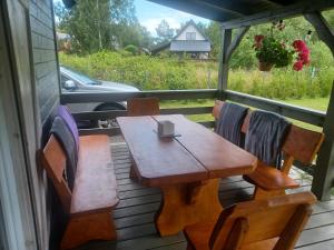 a wooden table and chairs on the back porch of a house at Kajetanówka in Jackowo