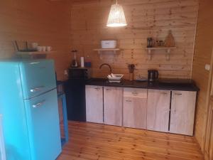 a kitchen with a blue refrigerator and wooden cabinets at Kajetanówka in Jackowo