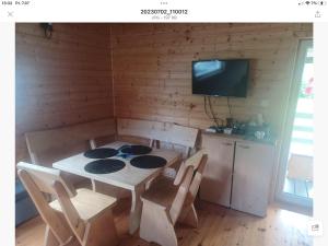 a dining room with a table and chairs and a tv at Kajetanówka in Jackowo