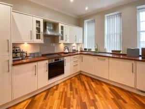 a kitchen with white cabinets and wooden floors at The Old Court House in Silloth
