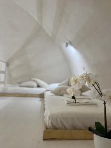a white bedroom with a bed and a plant at Antoniette-DimorePugliesi in Mottola