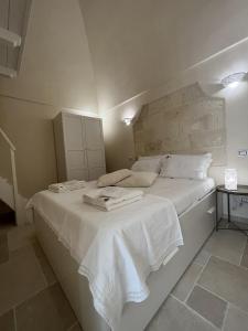 ein weißes Bett mit Handtüchern auf dem Zimmer in der Unterkunft Antoniette-DimorePugliesi in Mottola