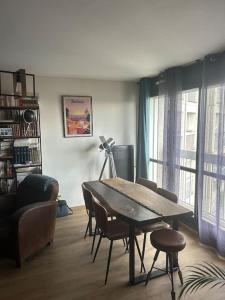 Una sala de estar con una mesa y sillas y un sofá. en Superbe T2 type loft proche Paris La Défense Arena et 30 min stade de France, en Puteaux