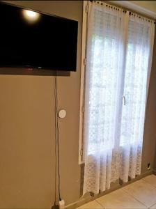 a window with white curtains and a flat screen tv at studio tranquille in Pavillons-sous-Bois