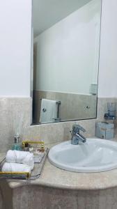 een badkamerbar met een wastafel en een spiegel bij Hawana salalah luxury apartment in Ma‘mūrah