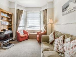 a living room with a couch and two chairs and a television at Seascape in Exmouth