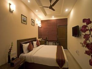 - une chambre avec un lit et un ventilateur de plafond dans l'établissement Red Maple Bed & Breakfast, à New Delhi