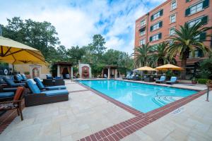 a swimming pool with chairs and umbrellas next to a building at Hotel Granduca Houston in Houston