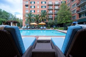 a large swimming pool with chairs and a building at Hotel Granduca Houston in Houston