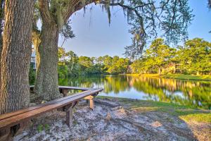 a wooden bench sitting next to a tree next to a lake at Hilton Head Vacation Rental Private Beach Access! in Hilton Head Island