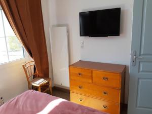 a bedroom with a dresser and a tv on the wall at Le Pavillon du Manoir de Conjon in Crouay
