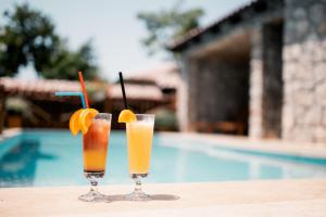 two glasses of orange juice sitting on a table next to a pool at Resort & Villas Carević in Budva