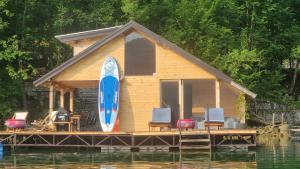 ein Haus auf einem Dock mit einem Surfbrett darauf in der Unterkunft Lake house Perucac in Bajina Bašta