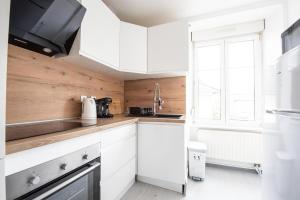 a kitchen with white cabinets and a window at L'Escapade Mulhousienne in Mulhouse