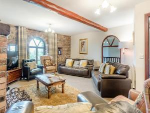 Gilcrux的住宿－伯溫班克鄉村別墅，客厅配有皮革家具和石墙
