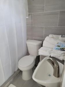La salle de bains est pourvue de toilettes blanches et d'un lavabo. dans l'établissement Ocean Village at Combate, à Cabo Rojo