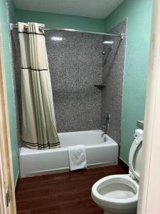 a bathroom with a bath tub and a toilet at Roadside Inn in Floresville