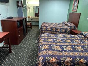 a hotel room with two beds and a television at Roadside Inn in Floresville
