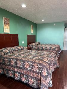 two beds in a hotel room with green walls at Roadside Inn in Floresville