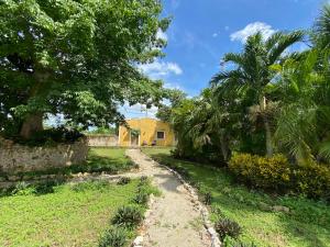 uma estrada de terra que leva a uma casa amarela com palmeiras em Villa en Hacienda noox Kankabal em Cholul