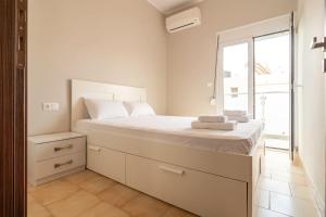 a white bedroom with a large bed and a window at Theros Apartment in Palaiochora