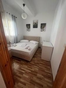 a bedroom with a white bed and a wooden floor at Villa Zoto in Himare