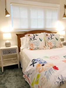 Un dormitorio con una cama con almohadas florales y una ventana en Liz Lane Cottage- entire guesthouse en Charleston