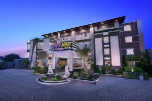 a large building with palm trees in front of it at Quest San Denpasar by ASTON in Denpasar