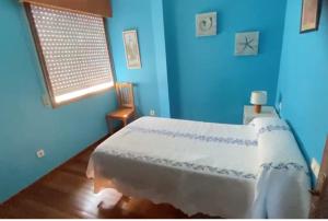 1 dormitorio con 1 cama con pared azul en Apartamento As Lagoas, en Bueu