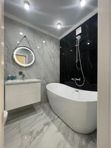een badkamer met een bad, een wastafel en een spiegel bij 1 комн квартира Тауельсиздик 34-2 18 этаж ЖК Silk Way in Promyshlennyy