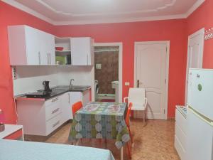 プエルト・デル・ロサリオにあるVivienda Perez Martinの赤い壁のキッチン、小さなテーブル(テーブルクロス付)