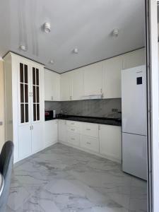 a kitchen with white cabinets and a white refrigerator at 1 комн квартира Тауельсиздик 34-2 18 этаж ЖК Silk Way in Promyshlennyy
