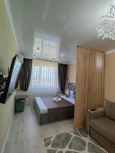 een slaapkamer met een bed en een tv en een bank bij 1 комн квартира Тауельсиздик 34-2 18 этаж ЖК Silk Way in Promyshlennyy