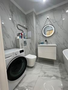 een witte badkamer met een wasmachine bij 1 комн квартира Тауельсиздик 34-2 18 этаж ЖК Silk Way in Promyshlennyy