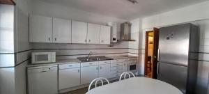 a kitchen with white cabinets and a sink and a refrigerator at Apartamento Tomar in Tomar