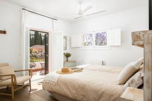 a white bedroom with a bed and a chair at Villa Elisa in Málaga