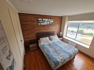 1 dormitorio con 1 cama con pared de madera en Departamento Laguna Bahía Algarrobo en Algarrobo