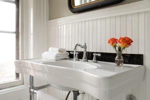 biała umywalka w łazience z kwiatami w wazie w obiekcie Rosemont Inn w mieście Utica