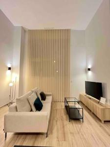 uma sala de estar com um sofá e uma televisão de ecrã plano em WeRentVLC - Espectacular Loft Duplex 1 hab em Valência