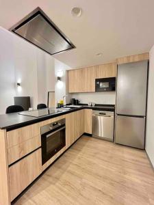 uma cozinha com armários de madeira e electrodomésticos de aço inoxidável em WeRentVLC - Espectacular Loft Duplex 1 hab em Valência