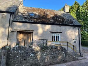 una vieja casa de piedra con una puerta delante de ella en The Cottage at Sychnant Farm, en Talgarth