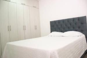 a white bedroom with a bed with a black headboard at Hermoso Apartamento en el Norte in Montería